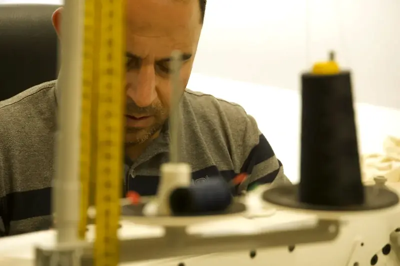 Lazki Isso stikt een kledingstuk op de naaimachine